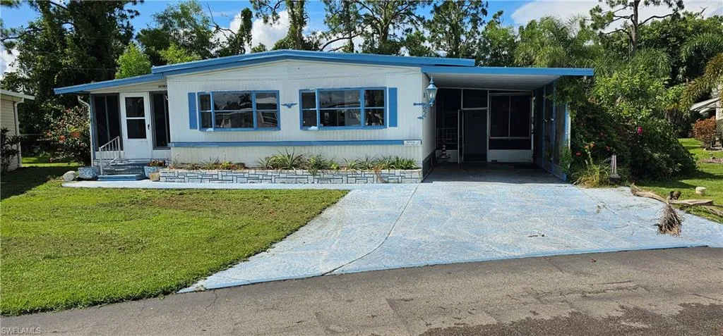 Manufactured / mobile home featuring a carport and a front lawn