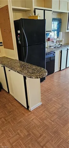 Kitchen featuring light parquet floors, white cabinetry, dishwasher, refrigerator, and sink