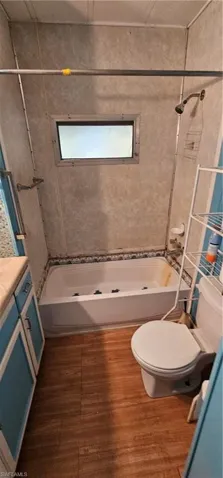 Full bathroom featuring tiled shower / bath combo, vanity, hardwood / wood-style flooring, and toilet