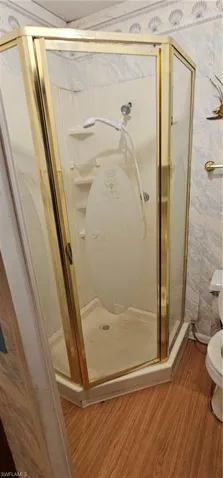 Bathroom featuring tile walls, toilet, walk in shower, and hardwood / wood-style floors
