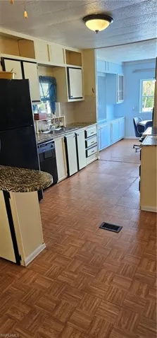 Kitchen featuring a textured ceiling, dark parquet flooring, refrigerator, and dishwasher