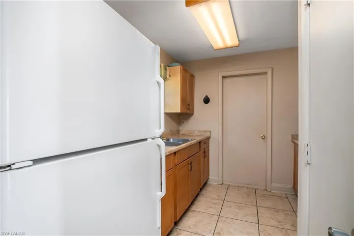 galley kitchen with laundry room behind door in background