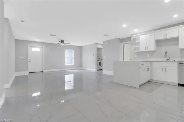 Kitchen with baseboards, a sink, open shelves, light marble finish floors, and recessed lighting