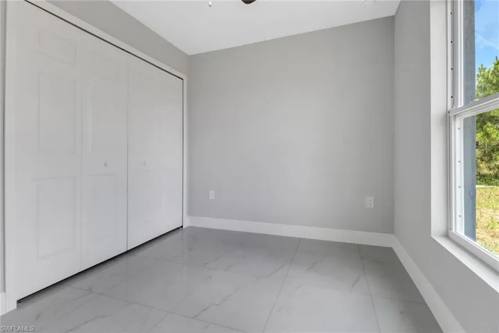 Unfurnished bedroom with marble finish floors, baseboards, and a closet