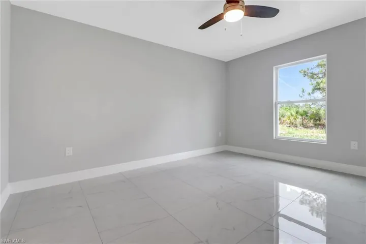 Unfurnished room with light marble finish flooring, baseboards, and a ceiling fan