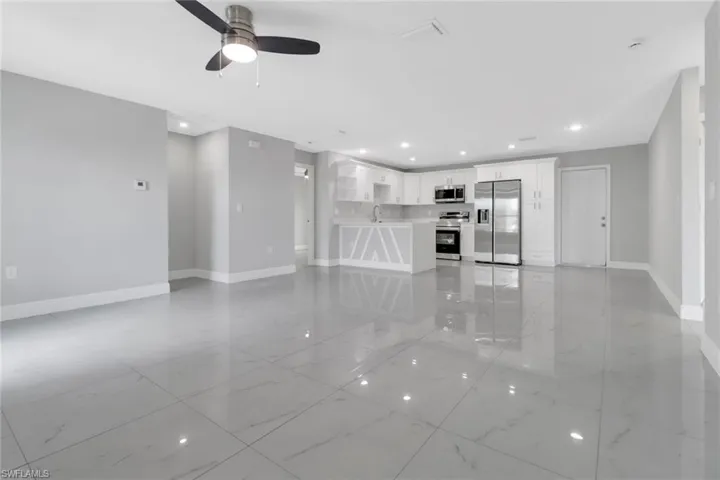 Unfurnished living room featuring baseboards, light marble finish flooring, a ceiling fan, and recessed lighting