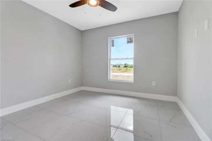Unfurnished room with light marble finish floors, baseboards, and a ceiling fan