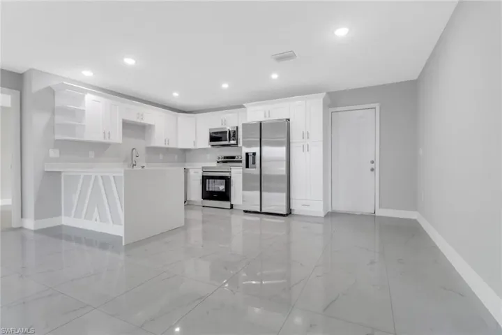 Kitchen with stainless steel appliances, baseboards, light marble finish flooring, open shelves, and light countertops
