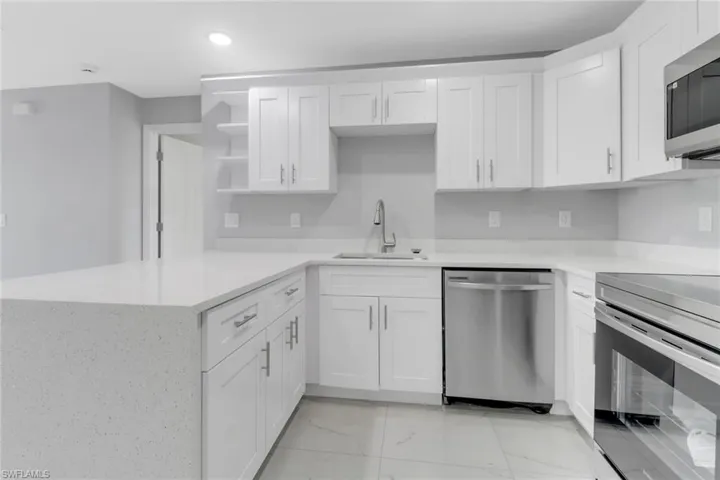 Kitchen with stainless steel appliances, a sink, light marble finish flooring, white cabinets, and open shelves