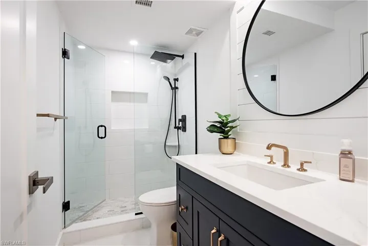 Bathroom on main floor with tile patterned flooring, toilet, vanity, and an enclosed shower