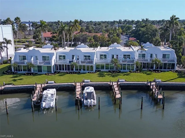 Rear view of property with a water view, a balcony, and a lawn