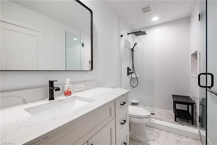 Bathroom featuring walk in shower, vanity, toilet, and tile patterned flooring
