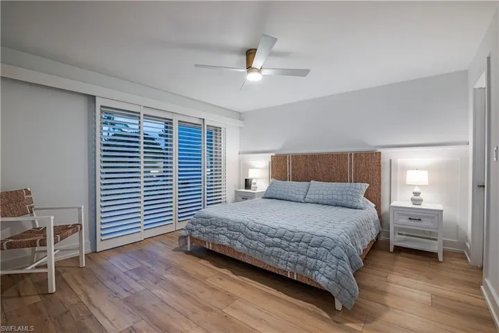 Main floor bedroom ceiling fan and light hardwood / wood-style flooring