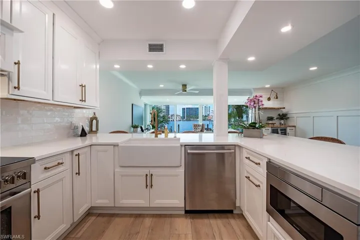 Kitchen with appliances with stainless steel finishes, light hardwood / wood-style flooring, ceiling fan, and white cabinetry