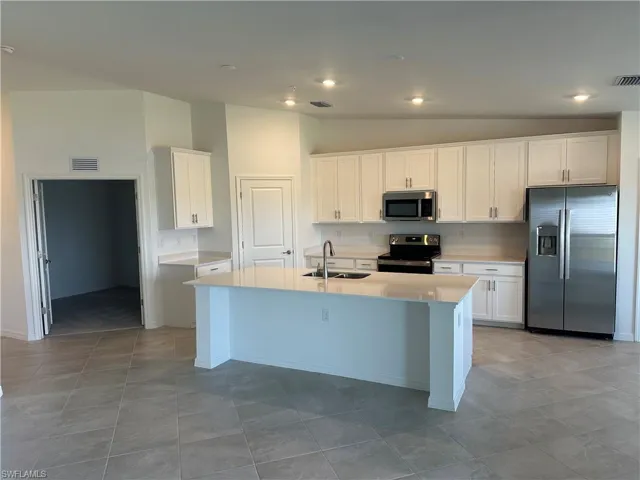 Kitchen featuring sink, a center island with sink, appliances with stainless steel finishes, and white cabinetry