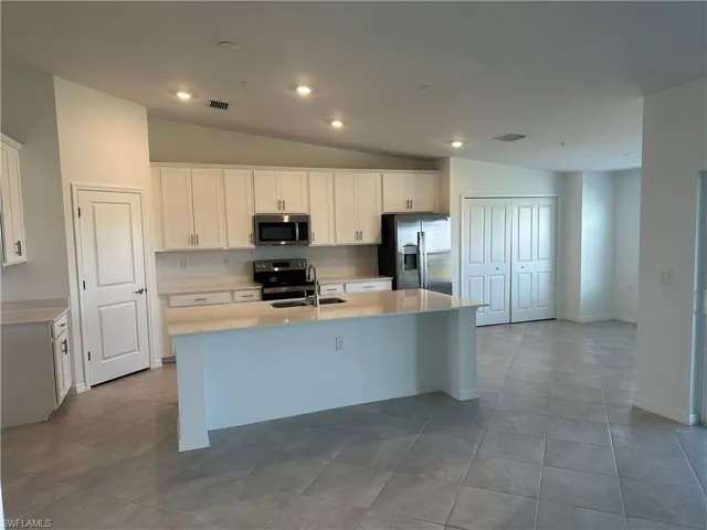 Kitchen with white cabinetry, an island with sink, and appliances with stainless steel finishes