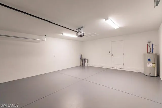 Garage featuring electric water heater and a garage door opener