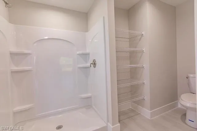 Bathroom with toilet, wood-type flooring, and walk in shower
