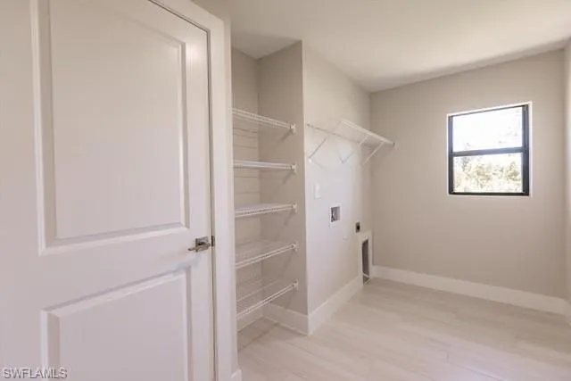 Washroom with hookup for a washing machine, light hardwood / wood-style flooring, and electric dryer hookup