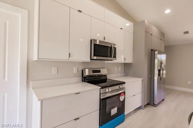 Kitchen featuring stainless steel appliances, white cabinetry, and light hardwood / wood-style flooring
