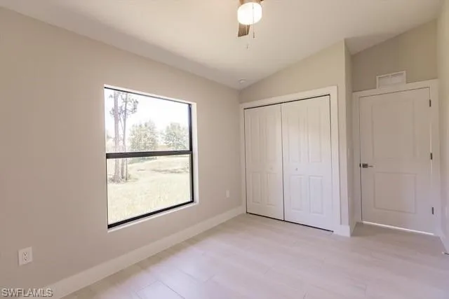 Unfurnished bedroom with ceiling fan, a closet, and vaulted ceiling