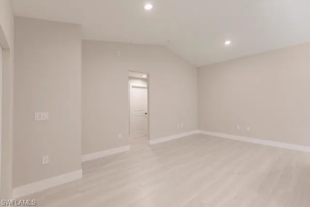 Unfurnished room with light hardwood / wood-style flooring and vaulted ceiling