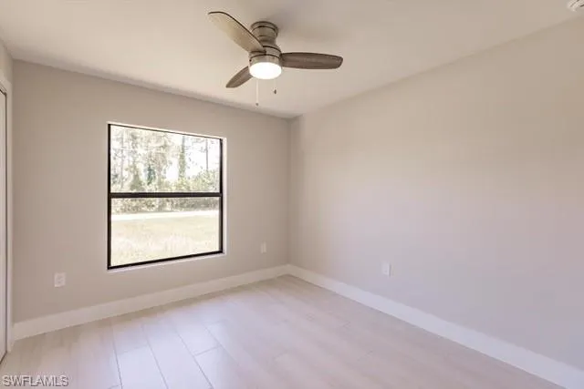 Empty room with ceiling fan and light hardwood / wood-style floors