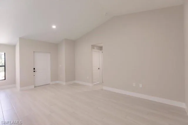 Empty room featuring light hardwood / wood-style floors and lofted ceiling