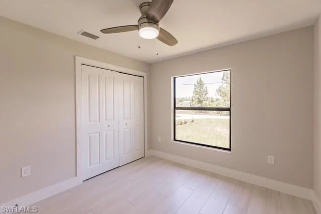 Unfurnished bedroom featuring multiple windows, ceiling fan, a closet, and light wood-type flooring