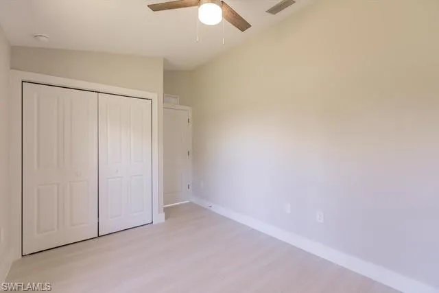 Unfurnished bedroom with ceiling fan, light hardwood / wood-style floors, vaulted ceiling, and a closet