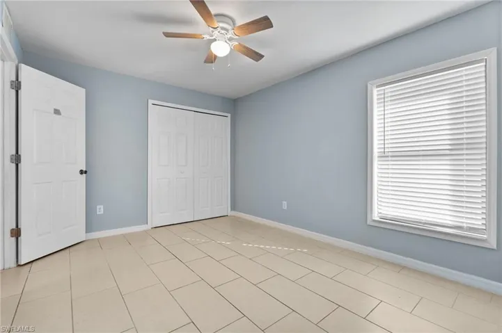 Unfurnished bedroom featuring ceiling fan, a closet, and light tile patterned floors