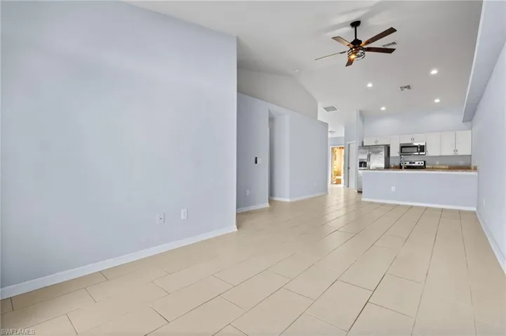 Unfurnished living room featuring vaulted ceiling, recessed lighting, a ceiling fan, and light tile patterned floors