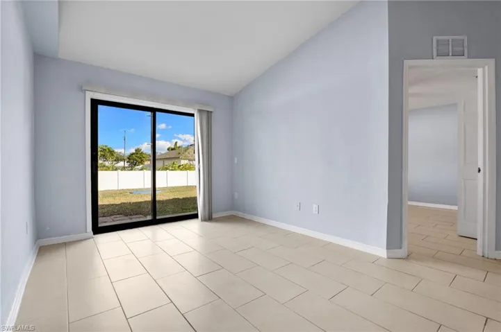 Empty room featuring vaulted ceiling and light tile patterned floors