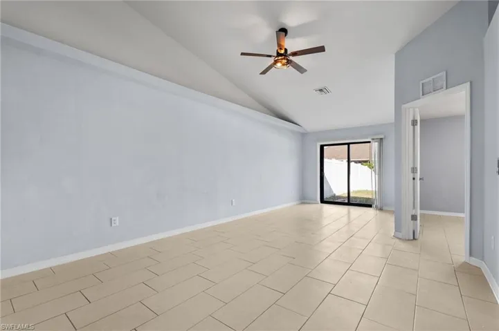 Unfurnished room featuring lofted ceiling, a ceiling fan, and light tile patterned flooring