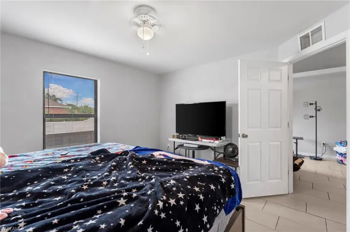 Bedroom with light tile patterned floors and a ceiling fan