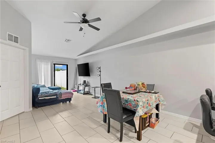 Dining space with lofted ceiling, a ceiling fan, and light tile patterned flooring