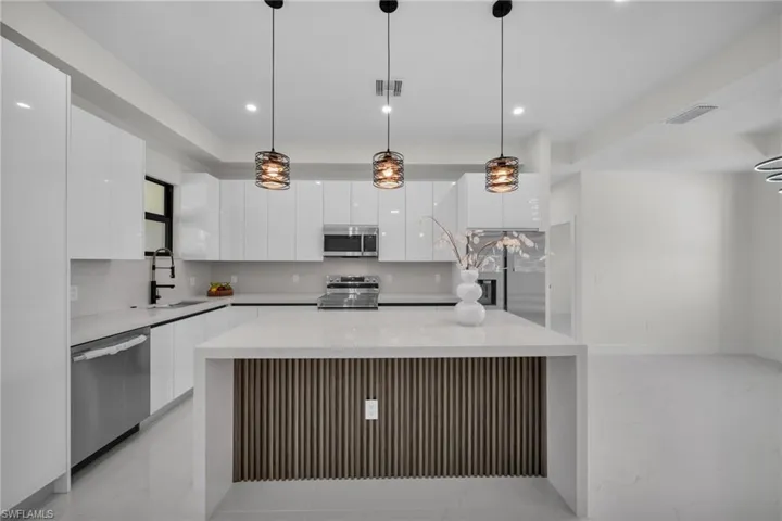 Kitchen with hanging light fixtures, modern cabinets, appliances with stainless steel finishes, and recessed lighting