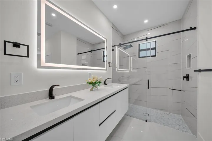 Bathroom with a marble finish shower, double vanity, and recessed lighting