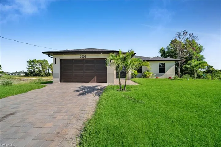 Single story home featuring stucco siding, decorative driveway, a garage, and a front yard