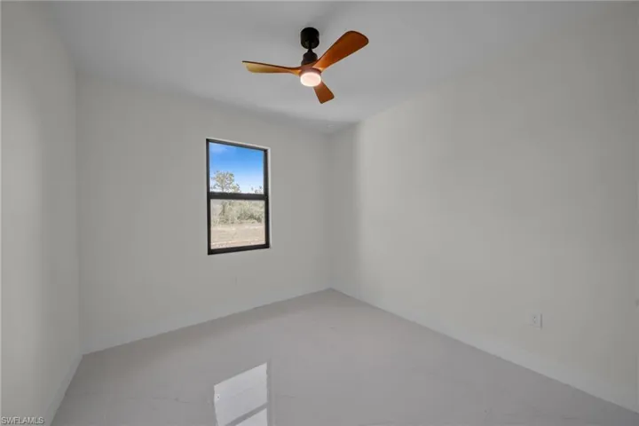Empty room with light marble finish floors and a ceiling fan
