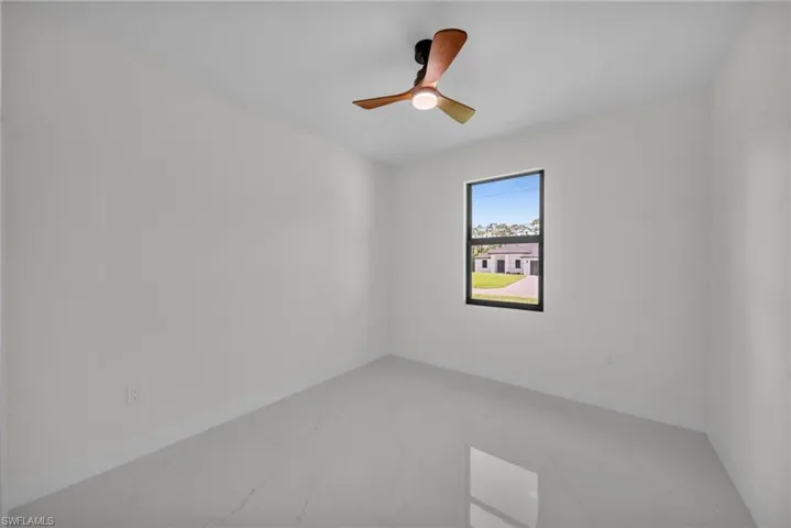 Empty room featuring marble finish floors and a ceiling fan