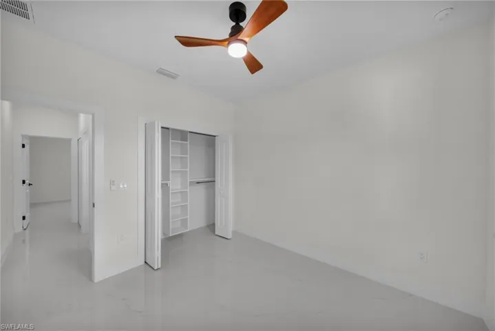 Unfurnished bedroom with ceiling fan and a closet