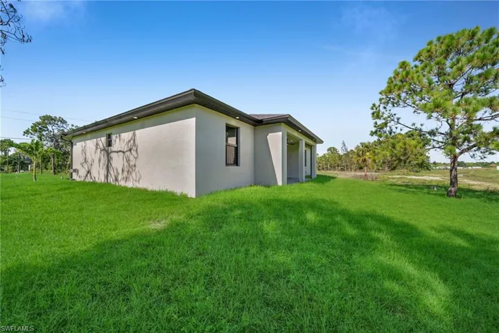 View of side of home with stucco siding and a lawn