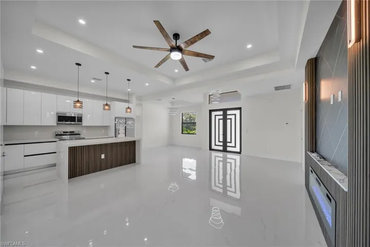 Kitchen featuring white cabinets, modern cabinets, a tray ceiling, open floor plan, and recessed lighting