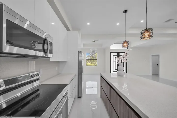 Kitchen featuring stainless steel appliances, modern cabinets, white cabinetry, hanging light fixtures, and recessed lighting