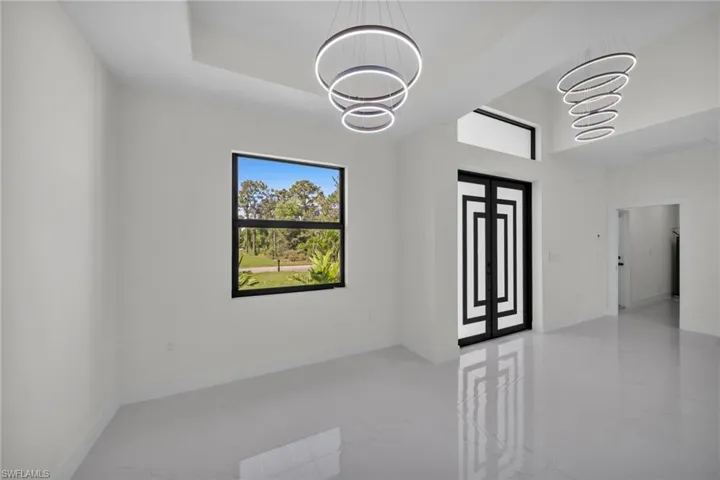 Empty room with healthy amount of natural light and a chandelier