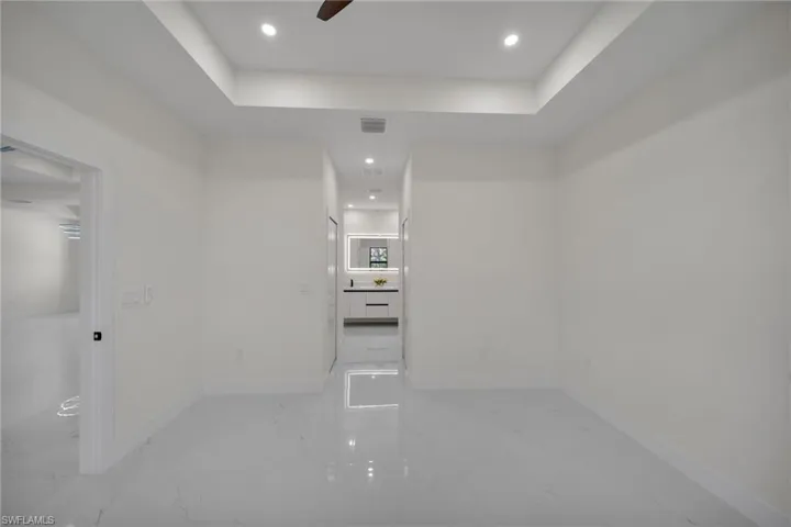 Spare room with a tray ceiling, light marble finish flooring, recessed lighting, and a ceiling fan