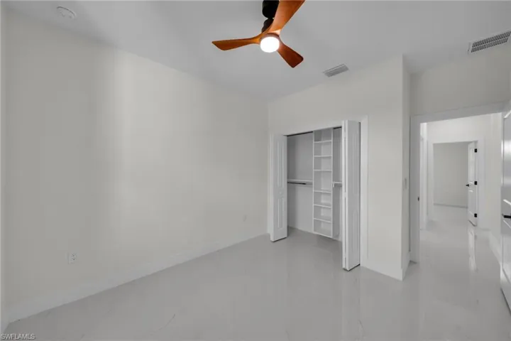 Unfurnished bedroom with a closet, ceiling fan, and light marble finish flooring