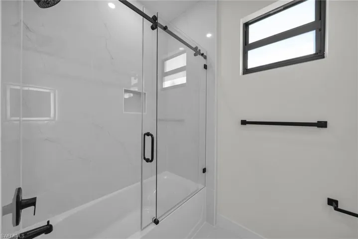 Bathroom featuring combined bath / shower with glass door and baseboards