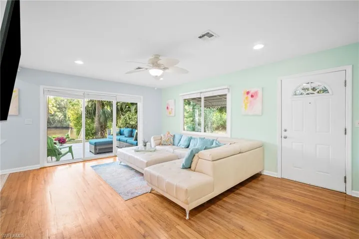 Living room featuring a wealth of natural light, visible vents, light wood-style flooring, and a ceiling fan